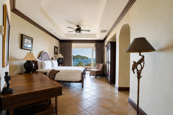 Primary bedroom at Marbella 6D featuring a king bed, writing desk, and private balcony with elevated views of Herradura Bay at Los Sueños Resort.