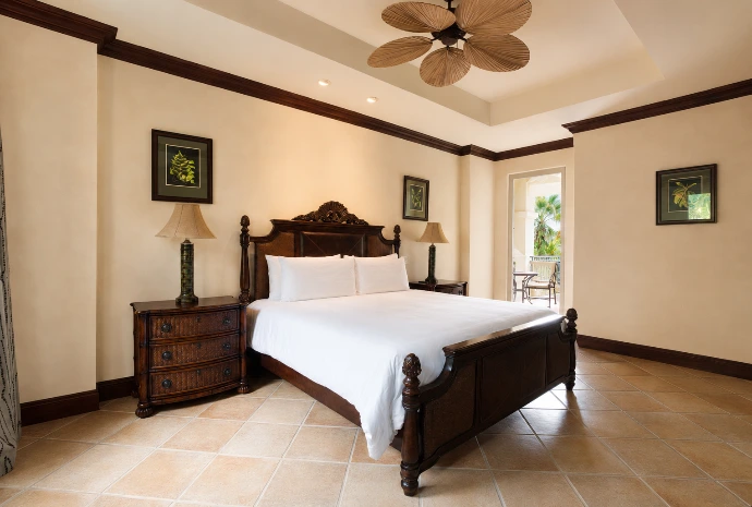 Guest bedroom at Marbella 6D featuring an elegant king bed, tropical-inspired furnishings, and direct access to a private balcony at Los Sueños Resort.