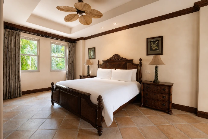 Guest bedroom at Marbella 6D featuring an elegant king bed, handcrafted tropical furnishings, and serene garden views at Los Sueños Resort.