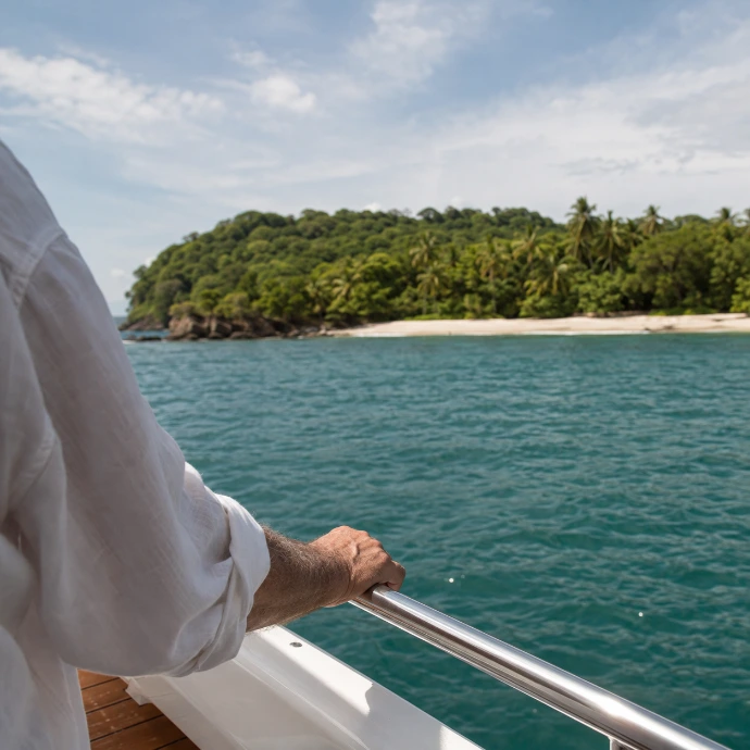 A guest holds the yacht’s railing as Tortuga Island comes into view across the Pacific during a private journey from Los Sueños Marina, Costa Rica.