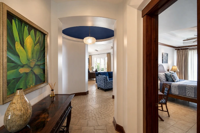 Interior hallway at Villa Tranquila leading into an elegant bedroom, featuring warm wood finishes, deep blue accents, and refined tropical design in Vista del Sol at Los Sueños Resort, Costa Rica.