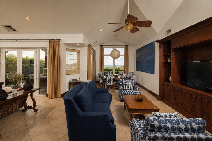 Open-concept living and dining room at Villa Tranquila, featuring elegant tropical interiors, rich wood finishes, deep blue accents, and Pacific views in Los Sueños Resort, Costa Rica.