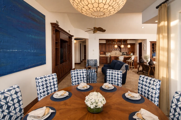Elegant dining room at Villa Tranquila, featuring rich wood finishes, refined blue accents, and an open-concept view toward the living room and kitchen at Los Sueños Resort, Costa Rica.