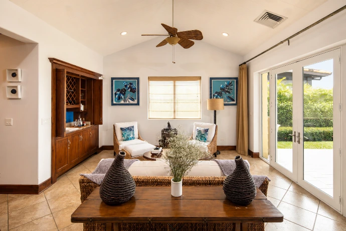 Elegant living room at Villa Tranquila featuring warm wood finishes, natural textures, a private bar, and views of the tropical garden at Los Sueños Resort, Costa Rica.