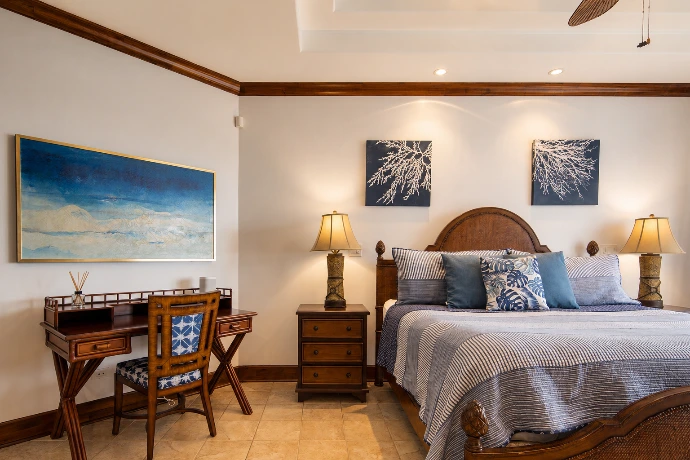 Spacious primary bedroom at Villa Tranquila featuring a king bed, elegant wood finishes, refined blue accents, and a dedicated workspace in Vista del Sol at Los Sueños Resort, Costa Rica.