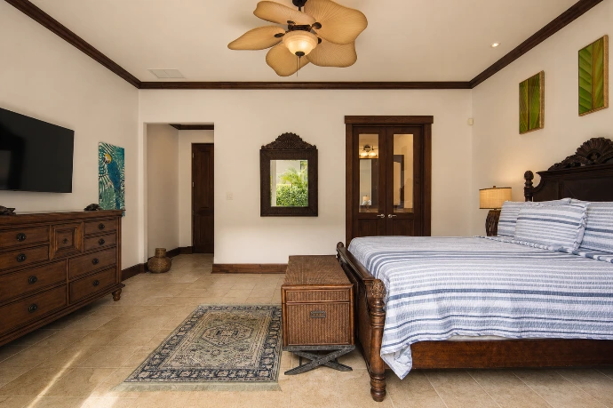 Elegant guest bedroom at Villa Tranquila featuring refined blue textiles, rich wood finishes, and warm tropical-inspired design in Vista del Sol at Los Sueños Resort, Costa Rica.