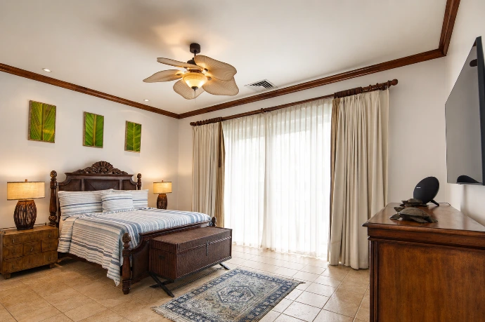 Bright guest bedroom at Villa Tranquila featuring elegant wood finishes, soft blue textiles, botanical artwork, and refined tropical design in Vista del Sol at Los Sueños Resort, Costa Rica.