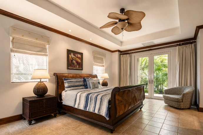 Elegant guest suite at Villa Tranquila featuring refined tropical interiors, rich wood finishes, soft blue accents, and direct garden views in Vista del Sol at Los Sueños Resort, Costa Rica.
