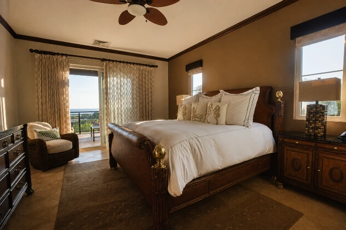 Primary bedroom at Altavista 1A featuring a king-size bed, warm natural light, elegant wood furnishings, and direct Pacific Ocean views at Los Sueños Resort, Costa Rica.