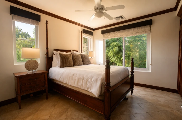 Guest bedroom at Altavista 1A featuring a four-poster bed, warm natural light, elegant wood furnishings, and tropical garden views at Los Sueños Resort, Costa Rica.