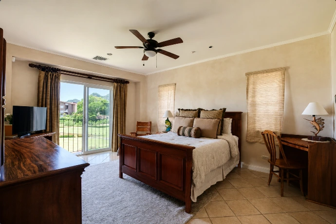 Spacious primary bedroom at Del Mar 2G, featuring a king-size bed, warm wood furnishings and natural light from the private balcony at Los Sueños Resort, Costa Rica.
