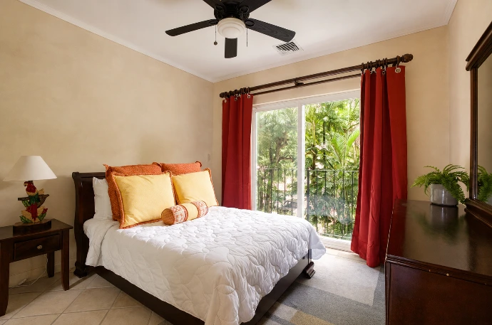 Comfortable twin guest bedroom at Del Mar 2G, featuring two beds, warm wood furnishings and natural light from the private balcony at Los Sueños Resort, Costa Rica.