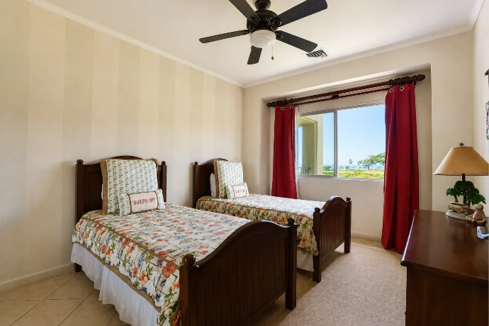 Twin guest bedroom at Del Mar 2G, featuring two beds, warm tropical interiors and views of La Iguana Golf Course and the Pacific Ocean at Los Sueños Resort, Costa Rica.