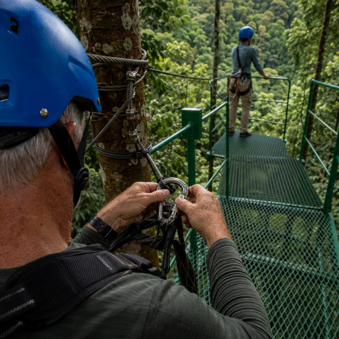 A guest prepares for a zipline adventure from a secure metal platform surrounded by tropical rainforest near Los Sueños, Costa Rica.