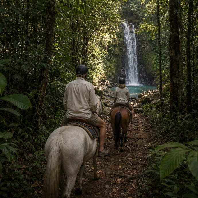 A couple rides horseback through the tropical rainforest toward a hidden waterfall during a full-day jungle adventure near Los Sueños, Costa Rica.