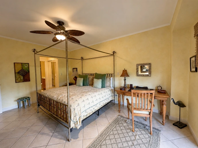 Warm primary bedroom at Del Mar 4P, featuring a four-poster bed, rich wood details and a relaxed garden-level setting within Los Sueños Resort, Costa Rica.