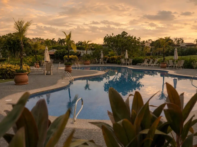 Community pool at golden hour near Del Mar 4P, surrounded by tropical gardens and peaceful scenery within Los Sueños Resort, Costa Rica.
