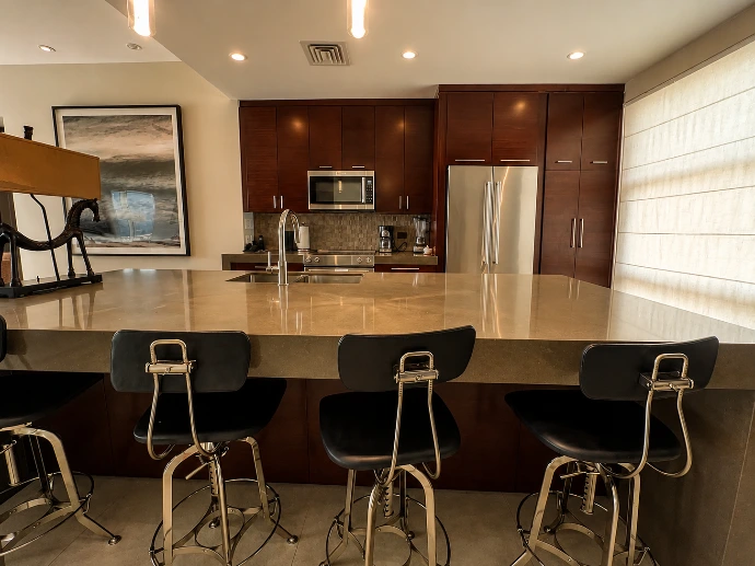 Contemporary kitchen at Montecielo 5A with dark wood cabinetry, stainless steel appliances, a spacious stone island, and breakfast bar seating.
