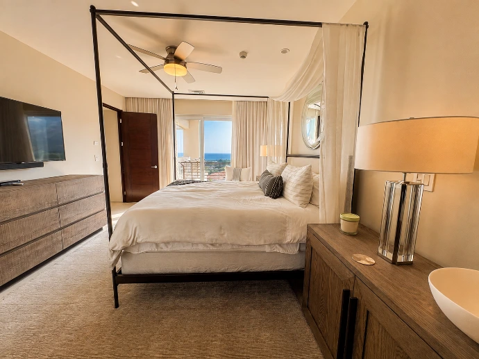 Primary bedroom at Montecielo 5A featuring a four-poster canopy bed, contemporary furnishings, and balcony views toward the Pacific Ocean in Los Sueños, Costa Rica.