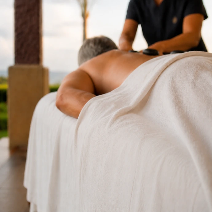 A guest relaxes beneath soft linens during a private hot-stone massage at Villa Tranquila, surrounded by the tropical setting of Los Sueños, Costa Rica.