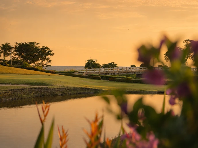Golden-hour view across La Iguana Golf Course, a reflective pond, and the Pacific Ocean at Los Sueños Resort.